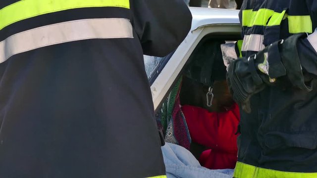 Fireman Cutting Out Windshield ; Firefighters rescuer team breaks car glass to save injured driver-demonstration exercise