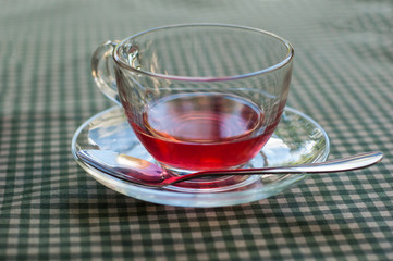 A cup of fruit tea on a checkered tablecloth.