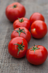 Several juicy red tomatoes on a wooden background.