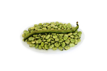 Freshly prepared podded broad beans on the white plate, isolated white background