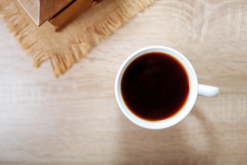 A cup of black coffee on a wooden table.