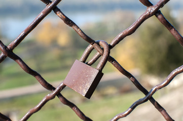 Metal padlock locked on weathered vintage metal mesh closeup