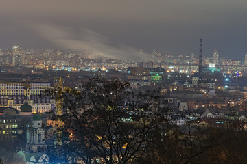 View of the ancient Podil district, factory with chemneys and modern Obolon district at background. Evening city panorama. Winter weekend evening. Kyiv, Ukraine