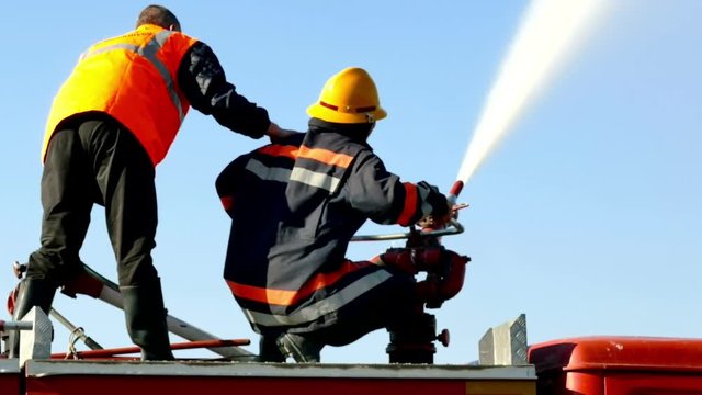 Firefighters in the fire fighting ; Two firefighters extinguished the fire with water cannon from a fire truck