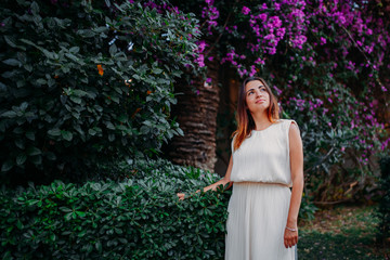 pretty girl in white dress on a background of flowers and bushes