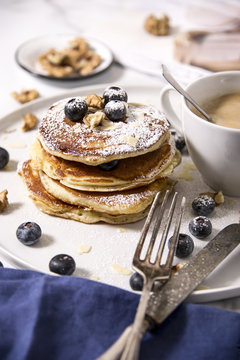 Pile of american pancakes with blueberries and powdered sugar.