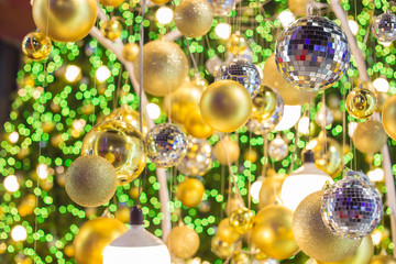 Golden Christmas ball hanging on Christmas tree with green bokeh in night time