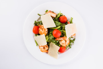 Fresh dietary salad with shrimps, ruccola, cherry tomatoes and Parmesan cheese. (Light background and close top view)