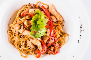 Italian pasta with chicken and peppers on a round plate on the white background (close top view)