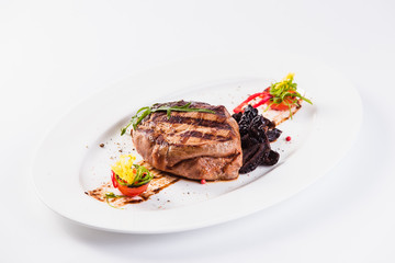 Grilled pork with prunes on an oval white plate close