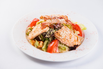salad with bacon and chicken on a white plate on a light background (close top view)