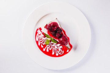 cheese cake with strawberries and raspberries on a white plate on a light background (close)