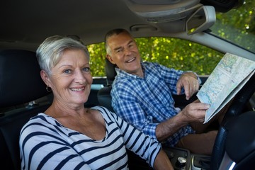 Senior couple with road map in car