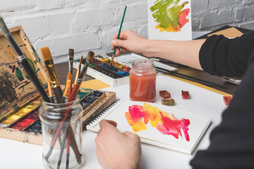 cropped shot of artist painting abstract picture at workplace