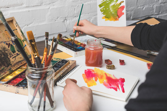 cropped shot of artist painting abstract picture at workplace