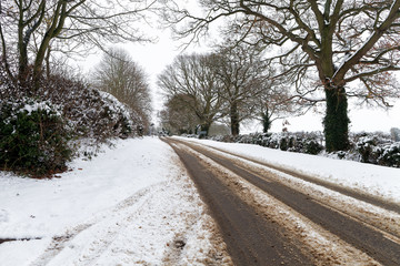 Snow covered road through winter countryside