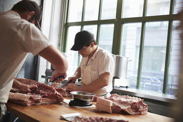 Two butchers cutting meat to sell at a butcher's shop