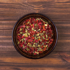 Red and green paprika in a bowl on a wooden background