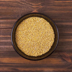White mustard seeds in a bowl on a wooden background