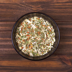 Spice mix - celery, parsley, parsnip, leeks, onions, dill, basil, carrot in a bowl on a wooden background