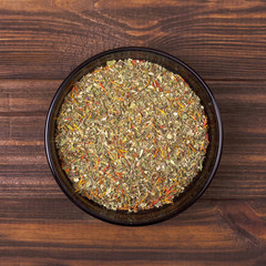 Spice mix - dill, parsley, basil, marjoram, oregano, saffron in a bowl on a wooden background