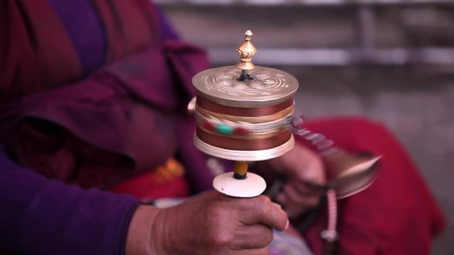 Closeup of spinning prayer wheel in tibetan monk's hand