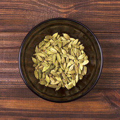 Cardamom seeds in a bowl on a wooden background