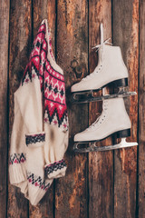 warm sweater and pair of white skates hanging on wooden wall