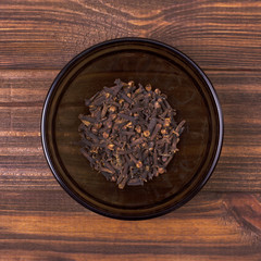 Clove in a bowl on a wooden background