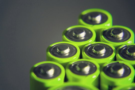 Stack of green AA batteries close up, electricity storage concept