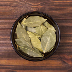 Bay leaves in a bowl on a wooden background