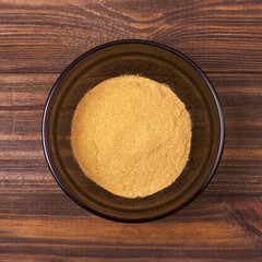 Cinnamon powder in a bowl on a wooden background