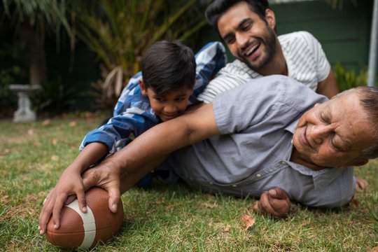 Happy family playing American football in yard