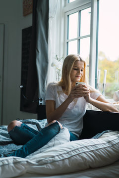 Woman on bed with cup of coffee