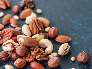 Background of nuts - cashew, pecan, pine nuts, hazelnuts - on dark blue background with copy space