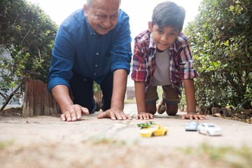 Boy and grandfather playing with toy cars