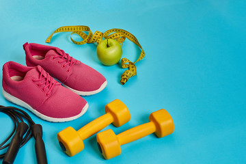 Flat lay of dumbbell, bottle of water, jump rope and sneaker, sport equipments, fitness items, top view