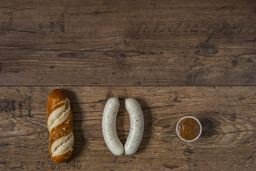 Ein paar Weisswürsten, Laugengebäck, süßer Senf in Reihe angeordnet Hintergrund rustikal Holzboden, A few white sausages, lye biscuits, sweet mustard arranged in row background rustic wooden floor