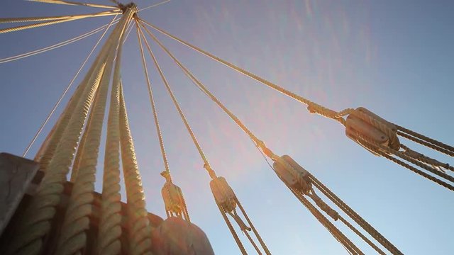 A sailboat mast seen from below, ropes and tackle of old ship