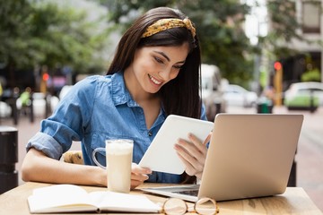 Obraz premium Woman holding tablet while sitting at cafe