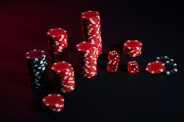 Dice and red and black chips on dark background