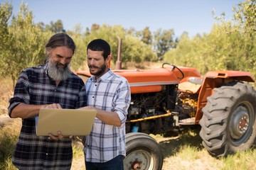 Friends using laptop in farm