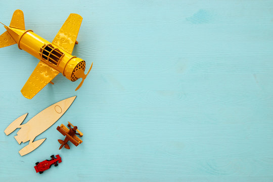 Top view image of retro yellow metal toy airplane over blue background.