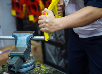 Plumber cutting metal tube. Industrial worker sawing pipe in workshop