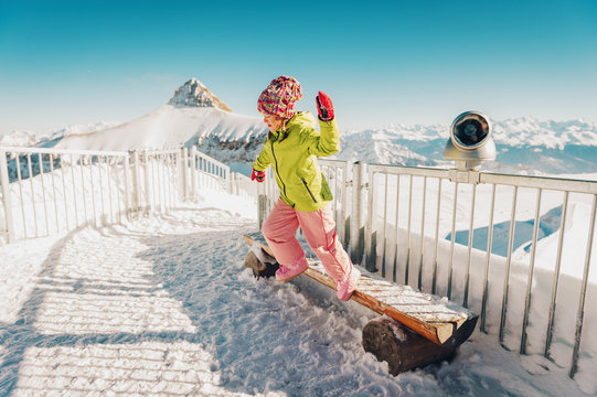 Kid girl playing with snow on the top of the mountain, winter vacation with children, family activities in Alps. Image taken in Glacier 3000, canton of Vaud, Switzerland