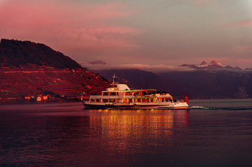 Steam boat with swiss and french flags floating on Lake Geneva or Lac Leman in the night