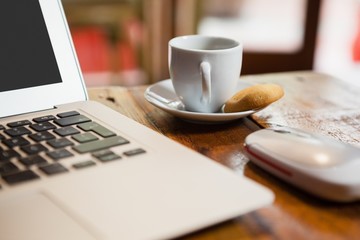 Close up of coffee cup by laptop on table