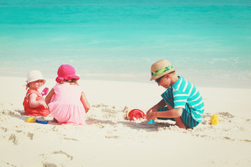 little boy and girls play with sand on beach