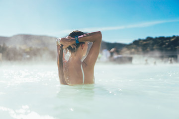 rear view of young woman relaxing in hot pool in Iceland