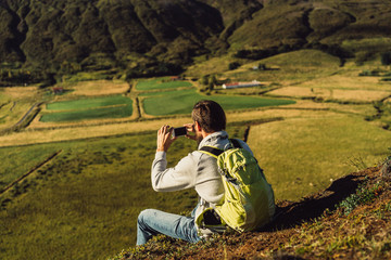 young man with backpack photographing beautiful icelandic landscape